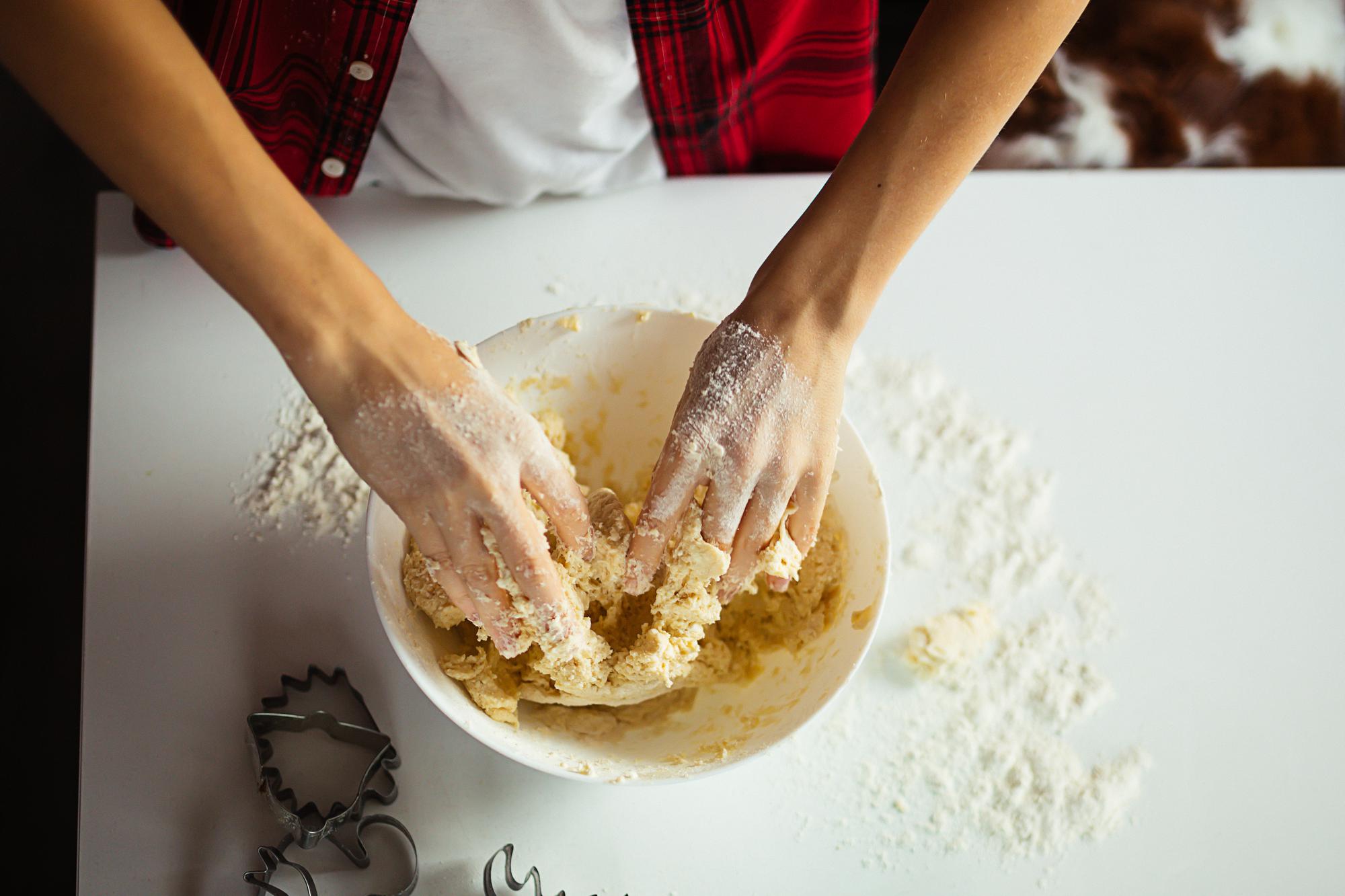 Close-up of hands kneading dough on marble